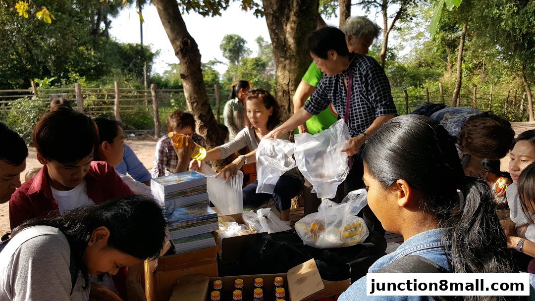 People gathered around a table with goods, some receiving items in plastic bags.