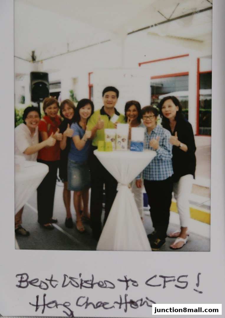 A group of people posing for a photo with products on a table.