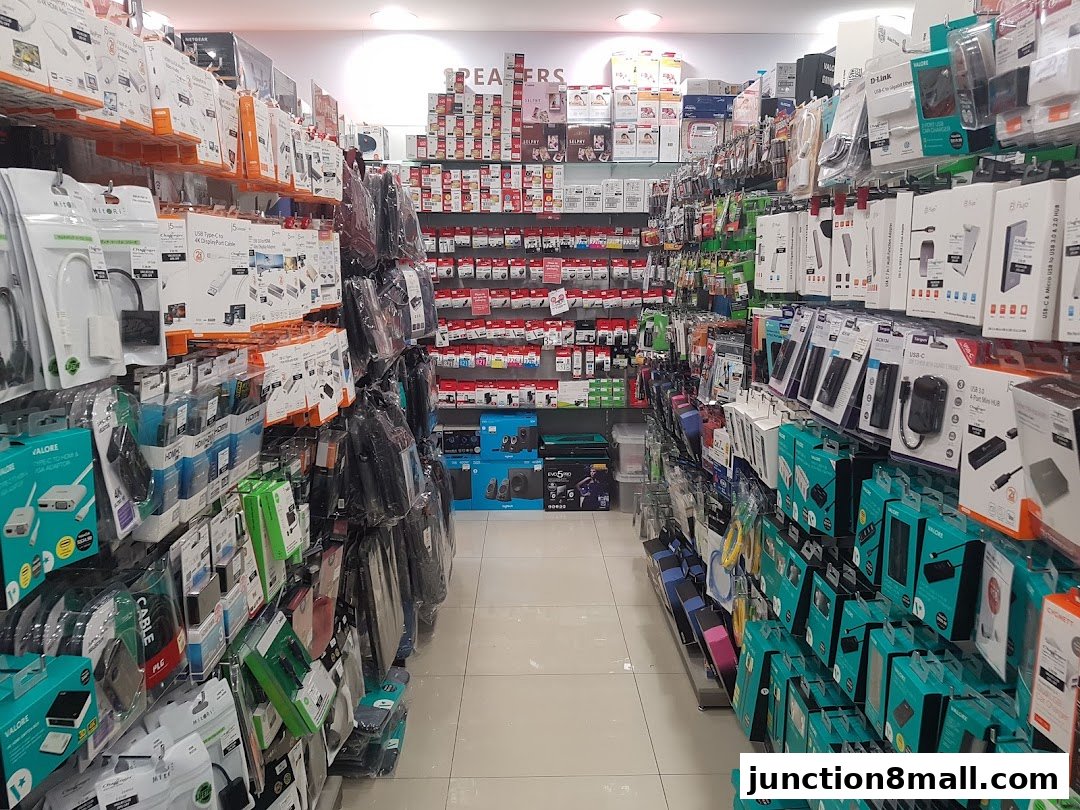 A wide aisle in a retail store filled with shelves of electronic accessories and gadgets.