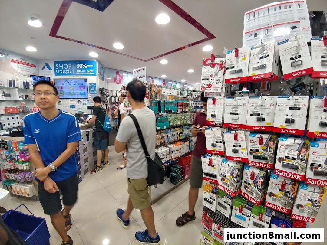 Interior of a Challenger electronics store with customers browsing and displays of SanDisk USB drives.