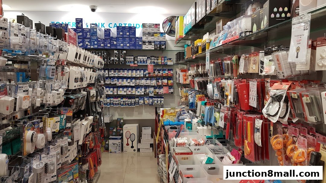 A wide aisle in a retail store filled with various electronic accessories and printer ink cartridges.