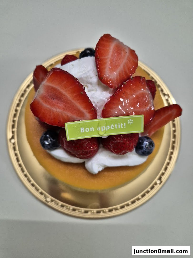 A delicious strawberry and blueberry cheesecake with whipped cream on a golden plate.