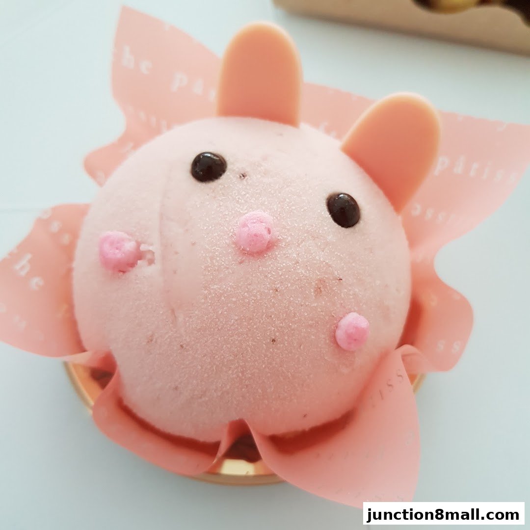 A cute pink bunny-shaped cake with chocolate eyes and pink frosting details.