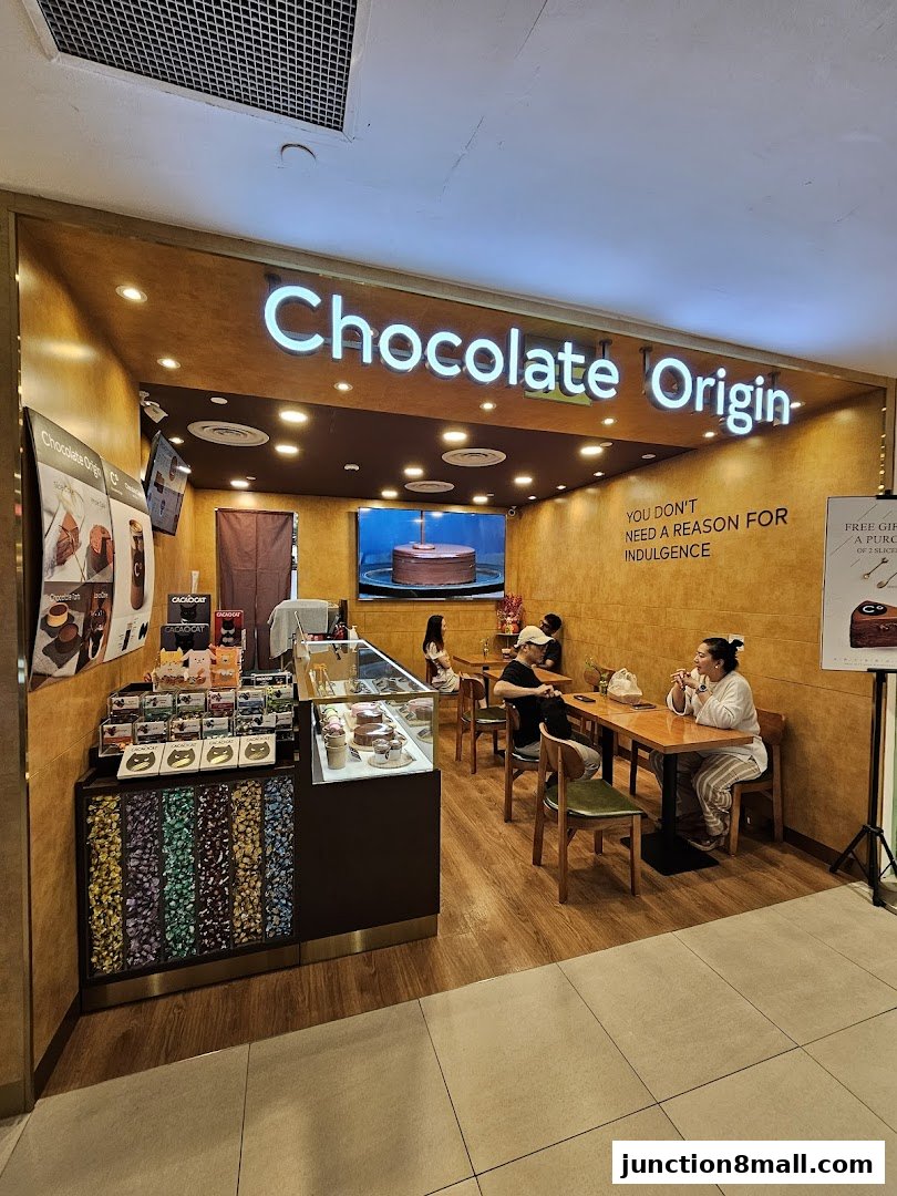 Interior of a Chocolate Origin shop with customers seated at tables and displays of chocolate.