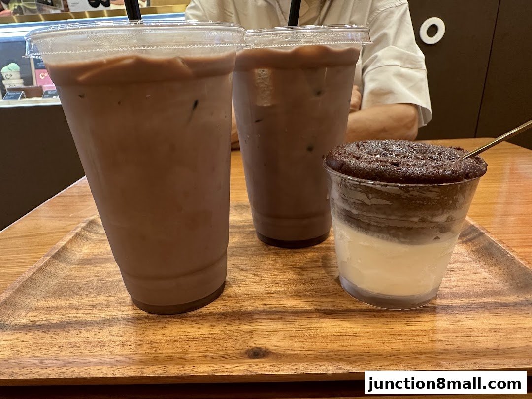 Three chocolate drinks and a dessert on a wooden tray at Chocolate Origin.