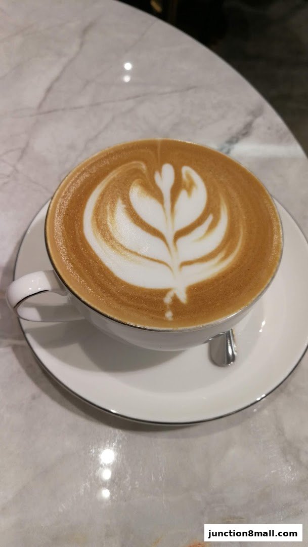 A close-up of a latte with intricate foam art on a marble table.