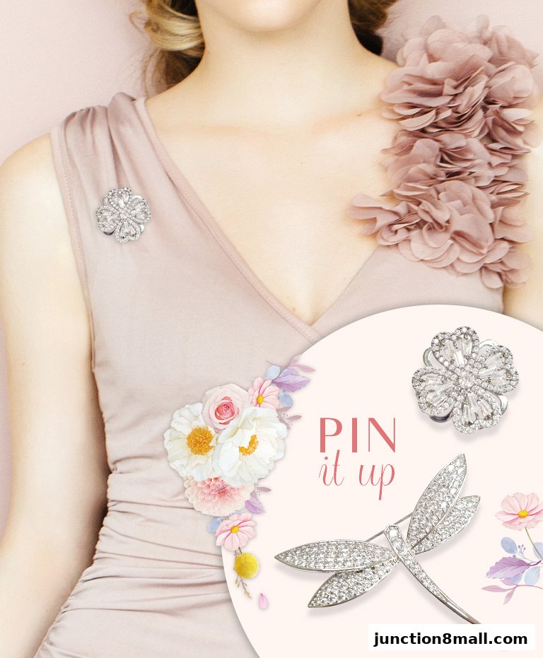 A model wearing a dress adorned with sparkling brooches and floral embellishments.