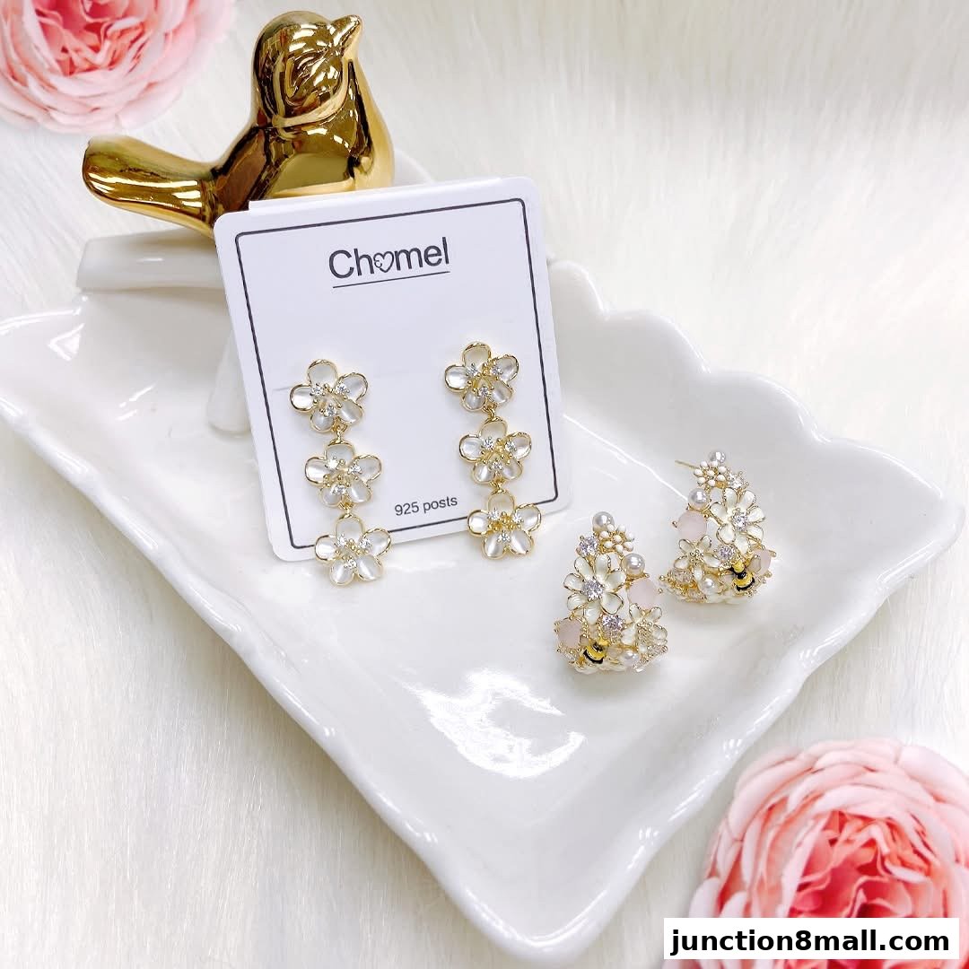 Chomel earrings with floral designs and pearl accents displayed on a white tray.