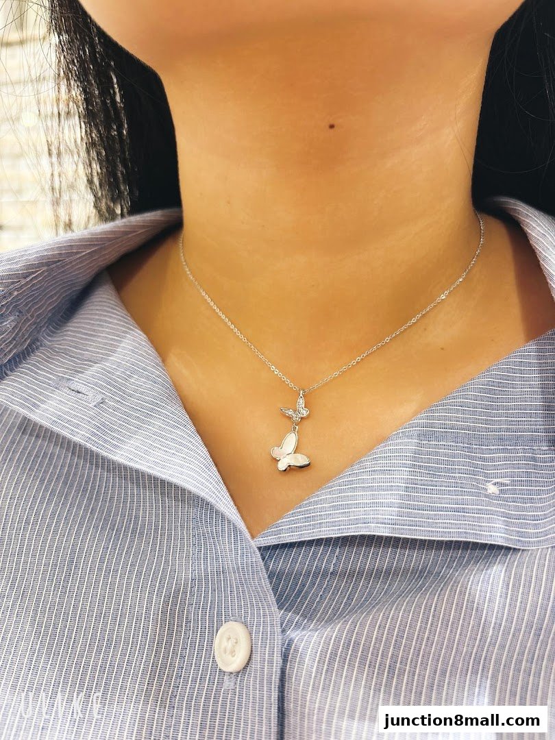 A woman wears a delicate silver necklace with two butterfly pendants.