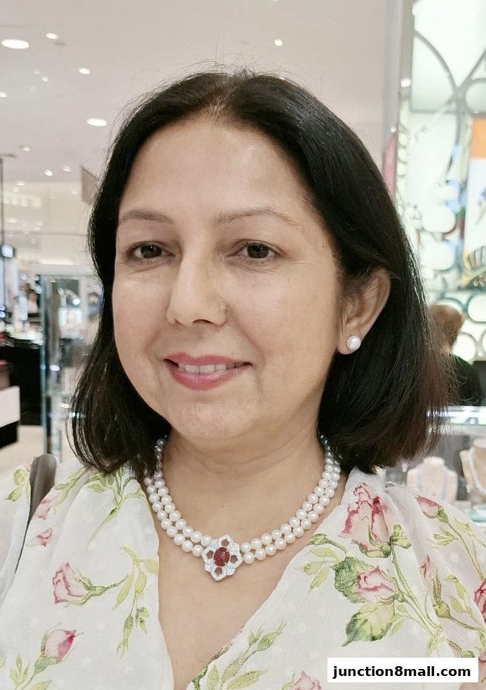A woman smiles, wearing a pearl necklace and earrings from Chomel.