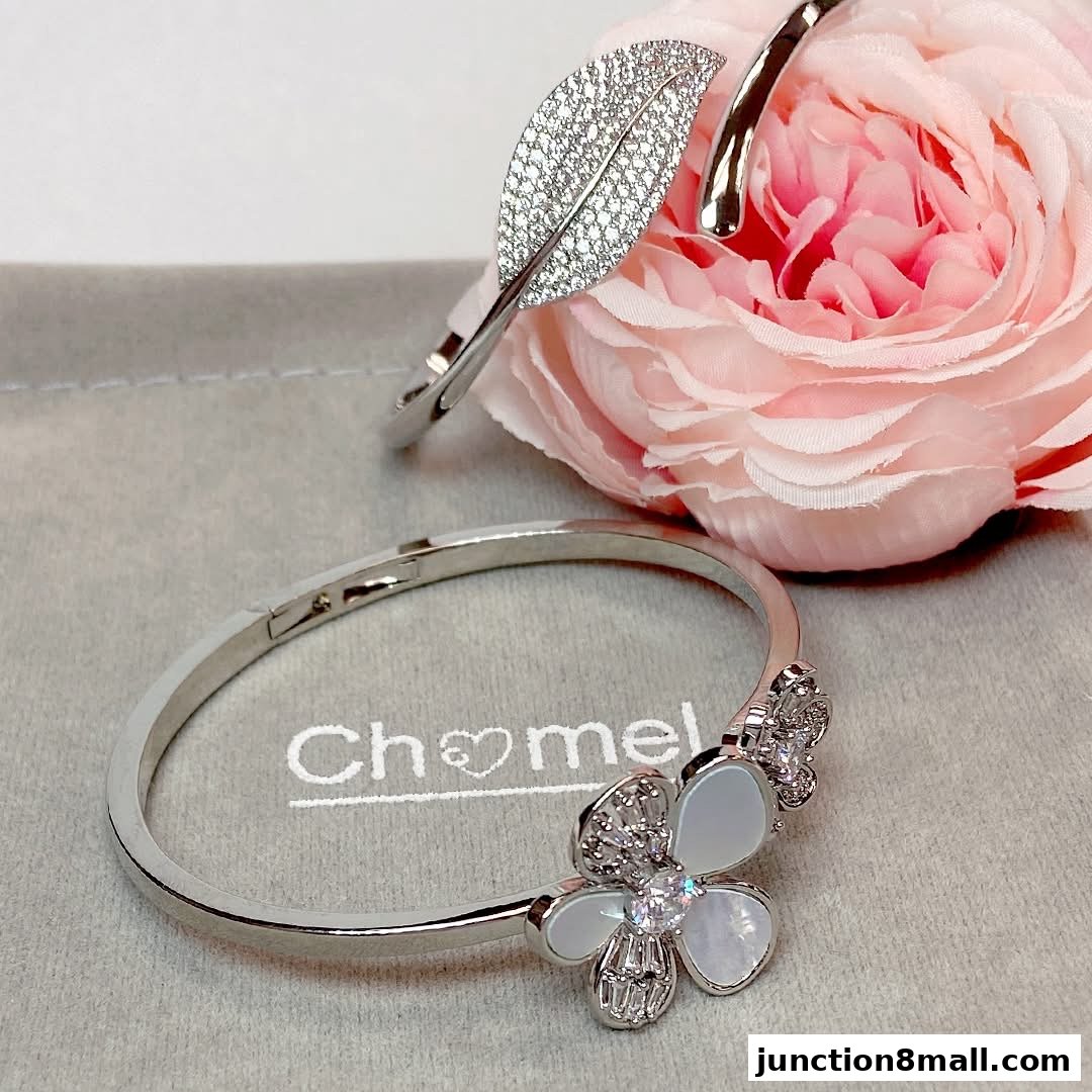 Two elegant silver bracelets, one with a leaf design and the other a flower, displayed with a pink rose.