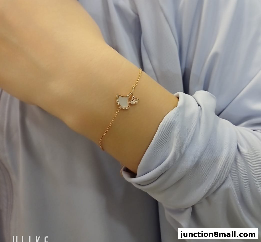 A delicate rose gold bracelet with a ginkgo leaf charm adorned with white stones.