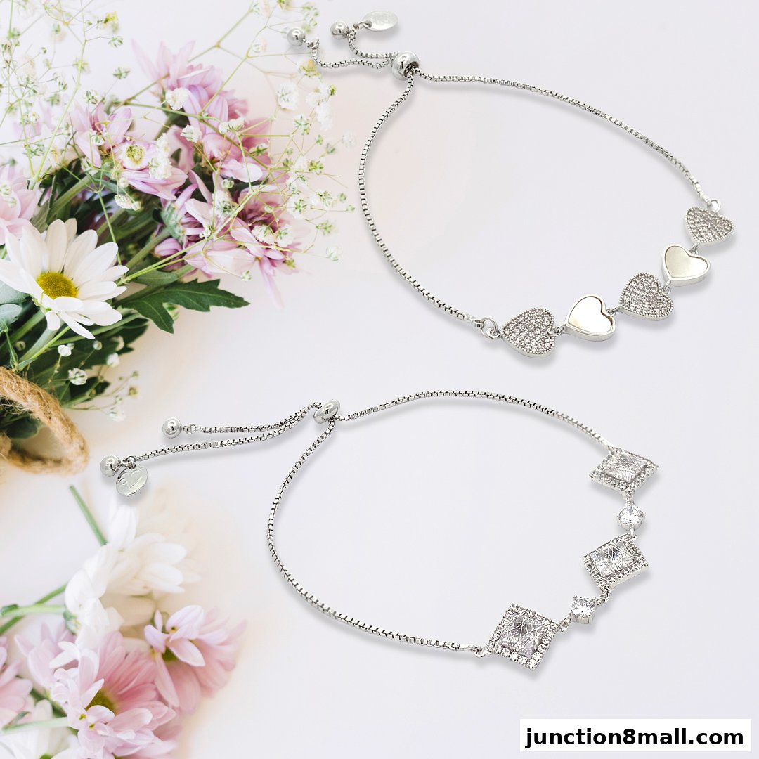 Two delicate silver bracelets with heart and square charms, displayed with flowers.