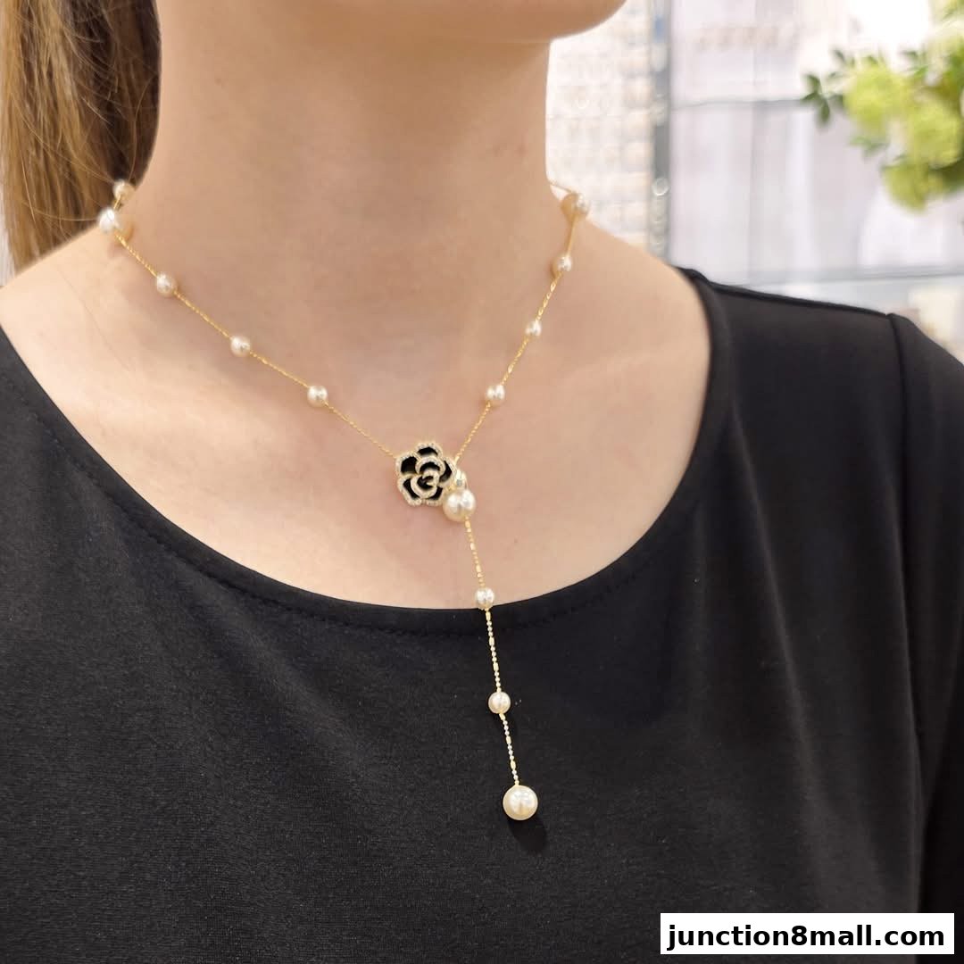 A woman wears a delicate gold necklace with pearls and a floral pendant.
