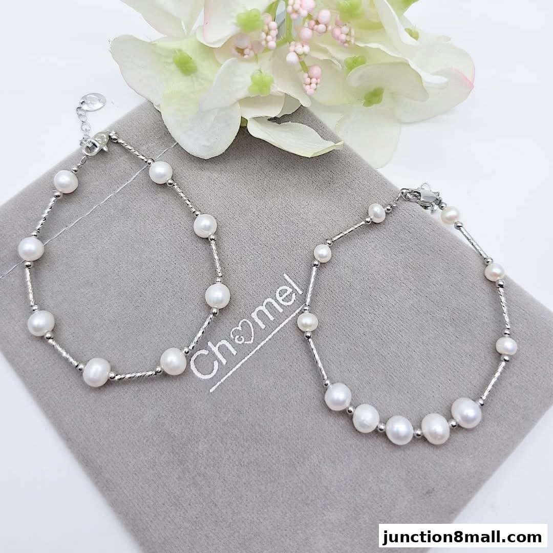 Two elegant pearl bracelets displayed on a grey cloth with flowers in the background.