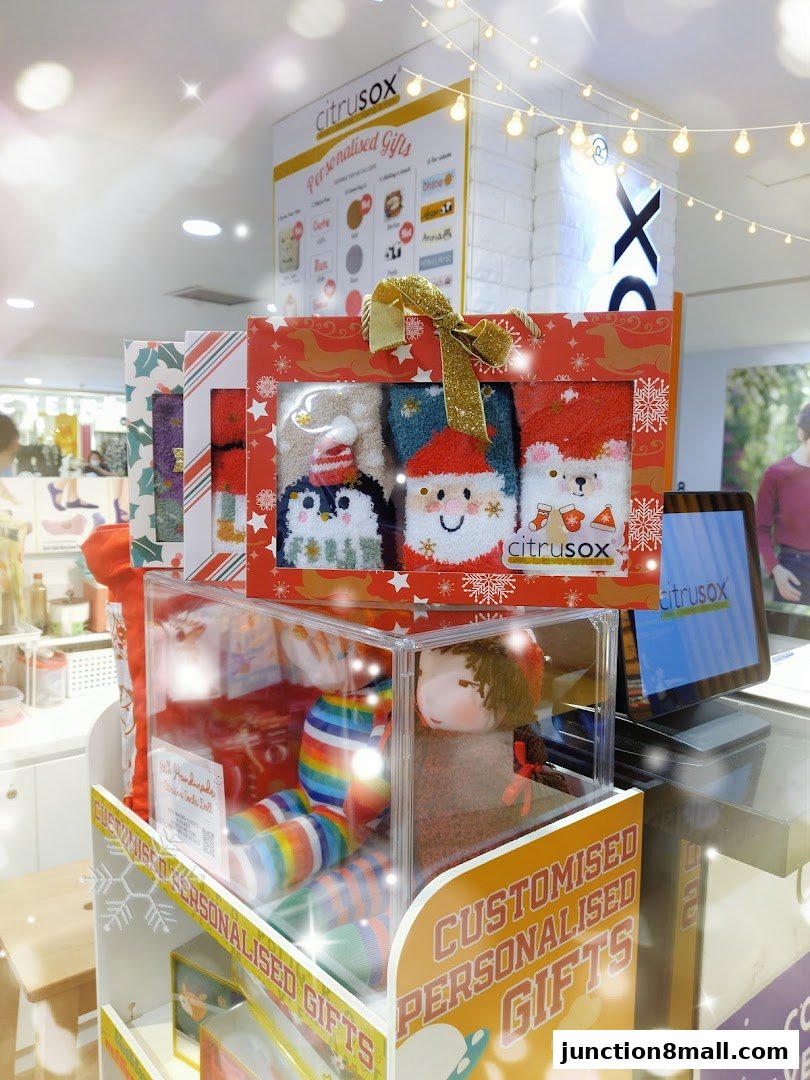 A display of Christmas-themed personalized gift sets featuring socks and dolls.