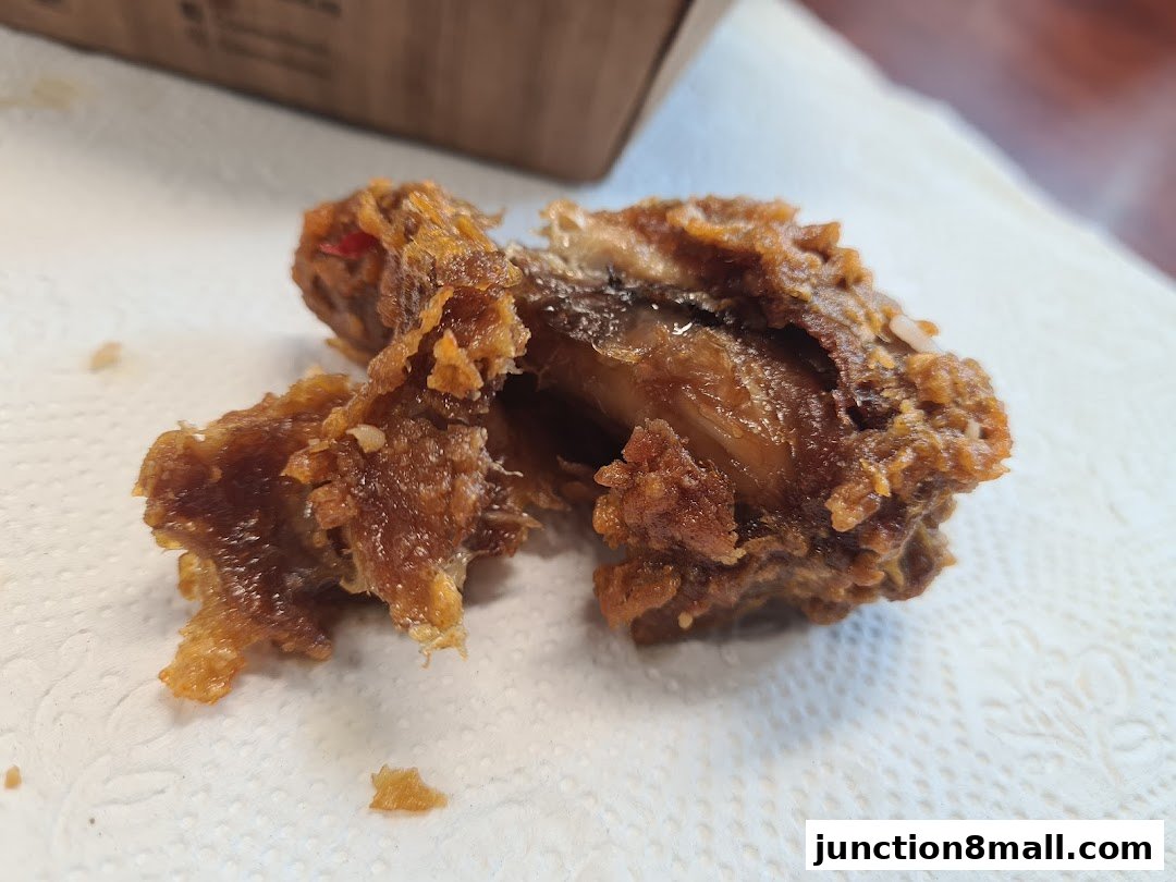 A close-up of a crispy, golden-brown fried chicken piece on a white napkin.