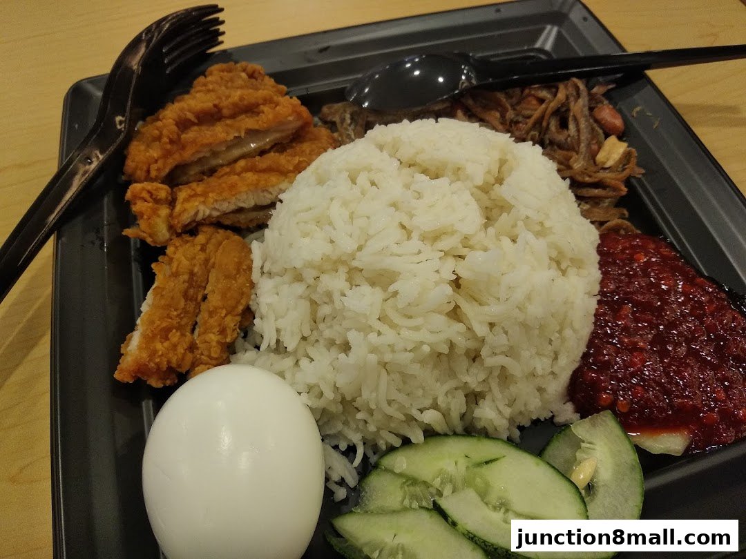 A plate of Nasi Lemak with fried chicken, rice, egg, sambal, and anchovies.