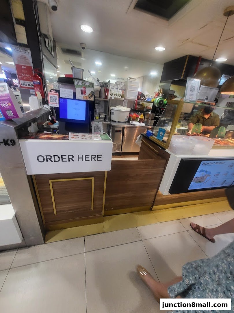 A view of the ordering counter at Crave Nasi Lemak, with a screen and 'ORDER HERE' sign.