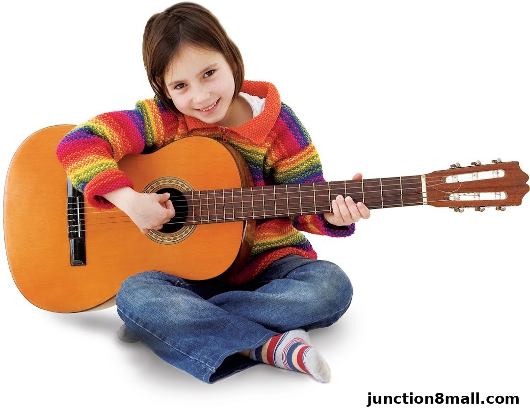 A young girl in a colorful sweater plays an acoustic guitar, smiling at the camera.