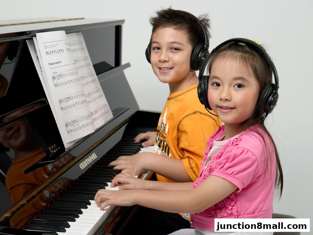 Two children wearing headphones play a piano with sheet music.