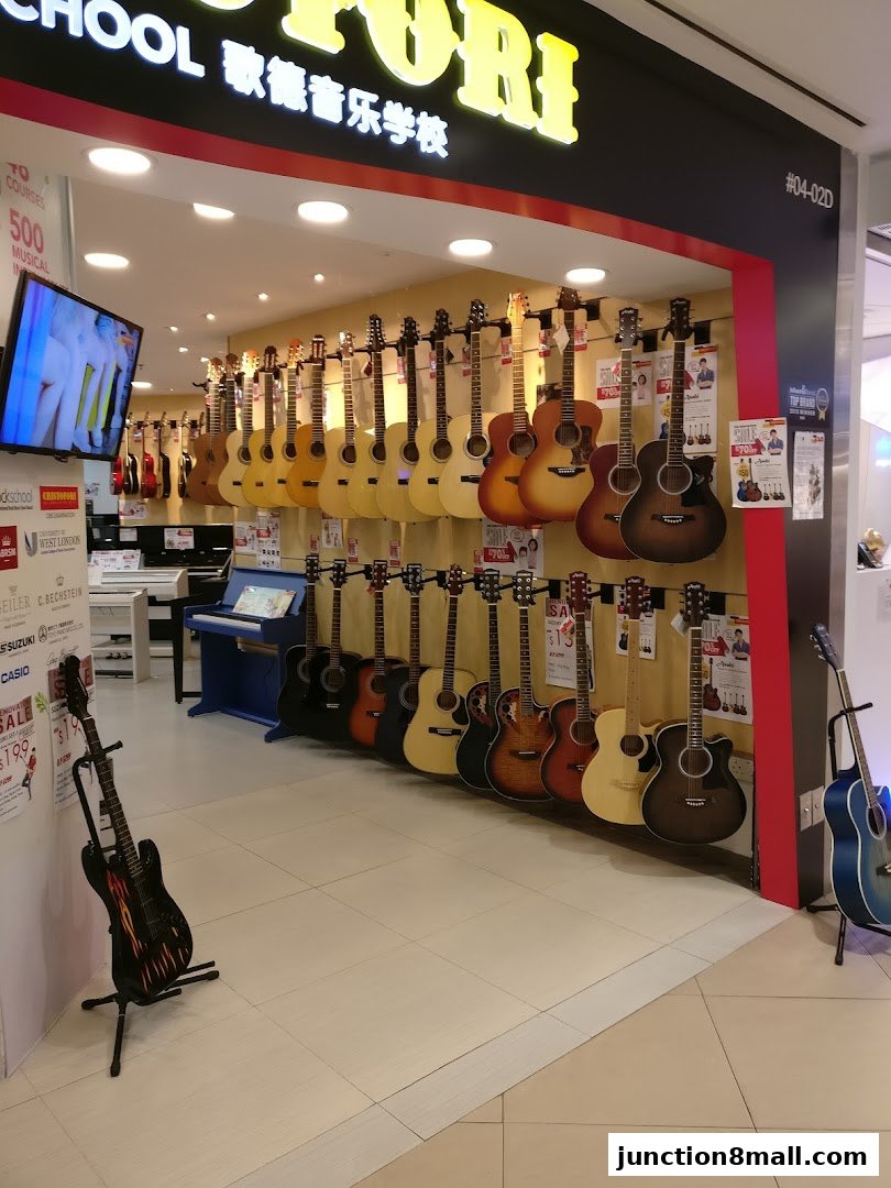 A music school shop front displaying a variety of acoustic guitars and a piano.