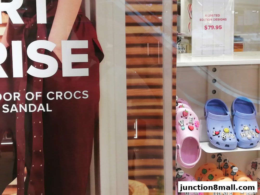 A display window showcasing Crocs sandals with various charms and a promotional sign.