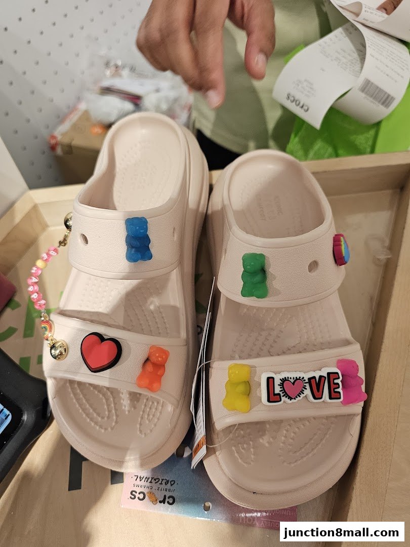 Close-up of two light pink Crocs sandals adorned with colorful Jibbitz charms.