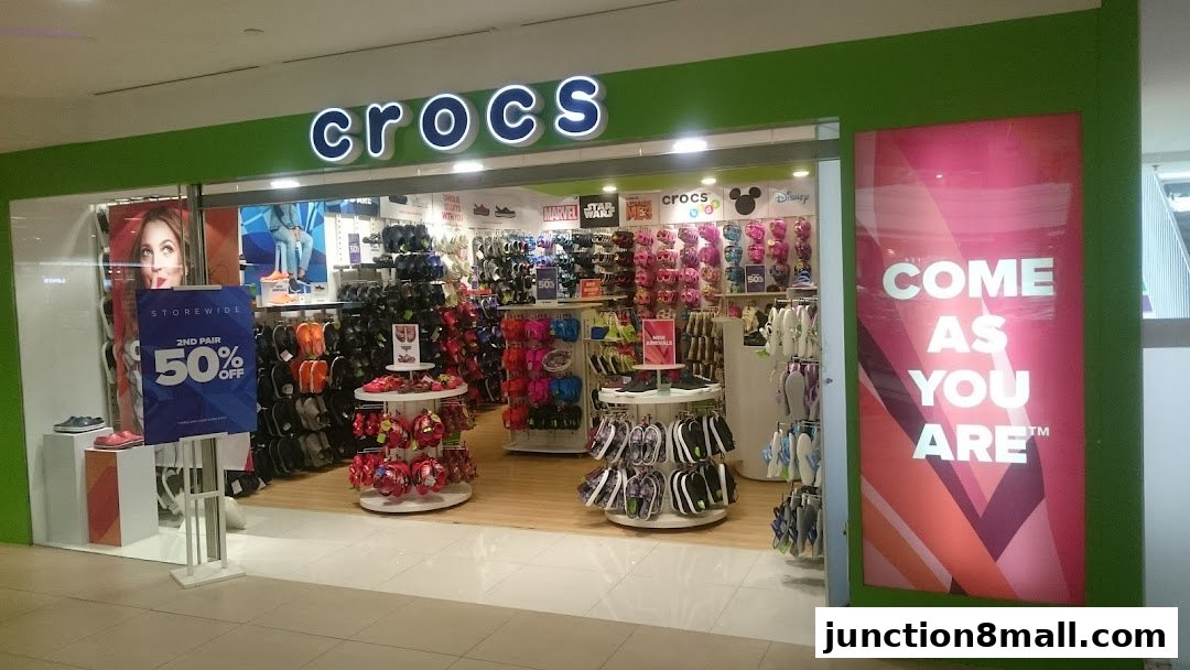 The Crocs store entrance displays a wide variety of colorful footwear and a storewide 50% off sale.