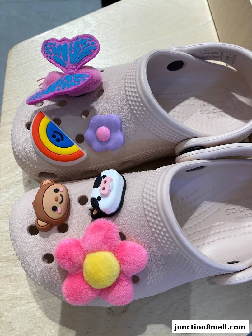 Close-up of light pink Crocs shoes adorned with colorful Jibbitz charms.