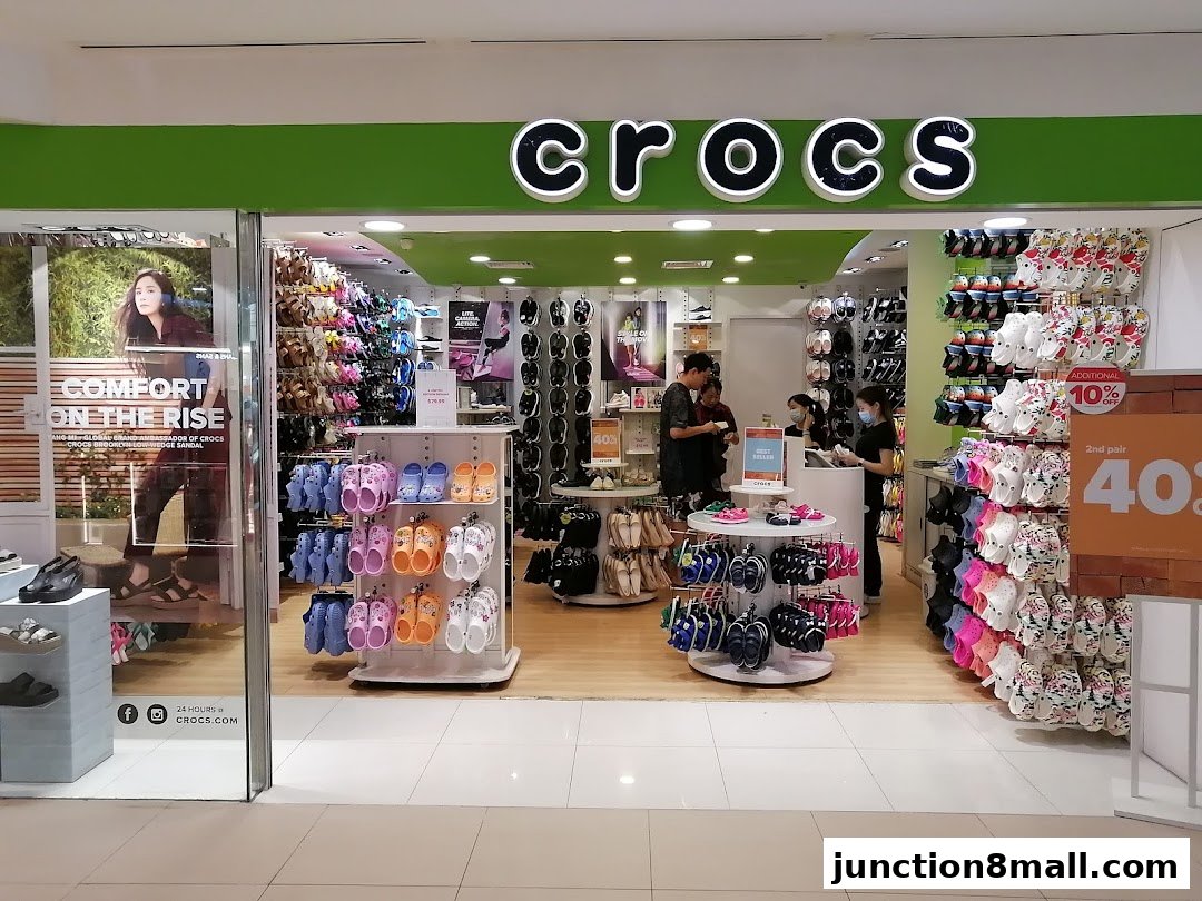 The Crocs store entrance displays a variety of colorful footwear and promotional signage.