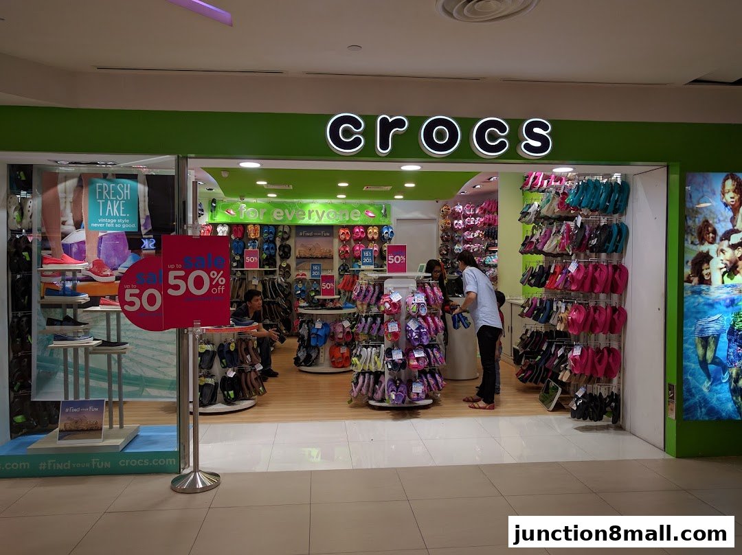 The Crocs store entrance displays a large sale sign and a variety of colorful footwear.