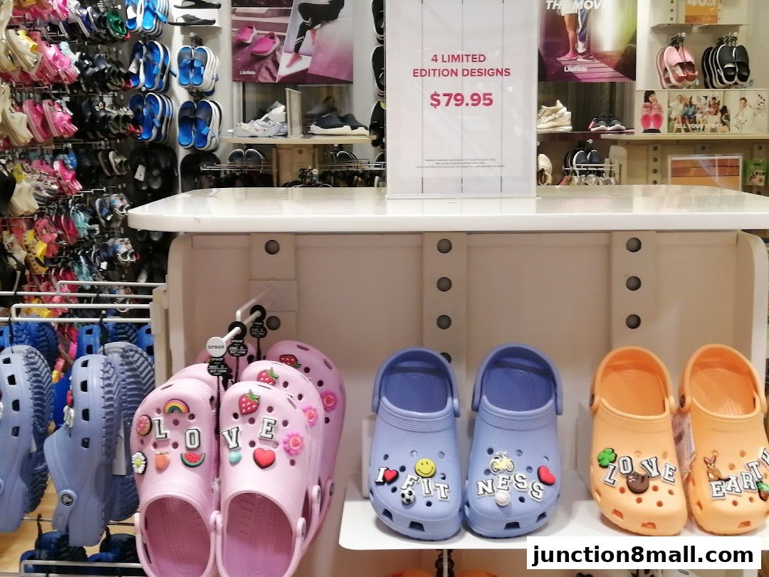A display of colorful Crocs shoes with various charms and a sign advertising limited edition designs.