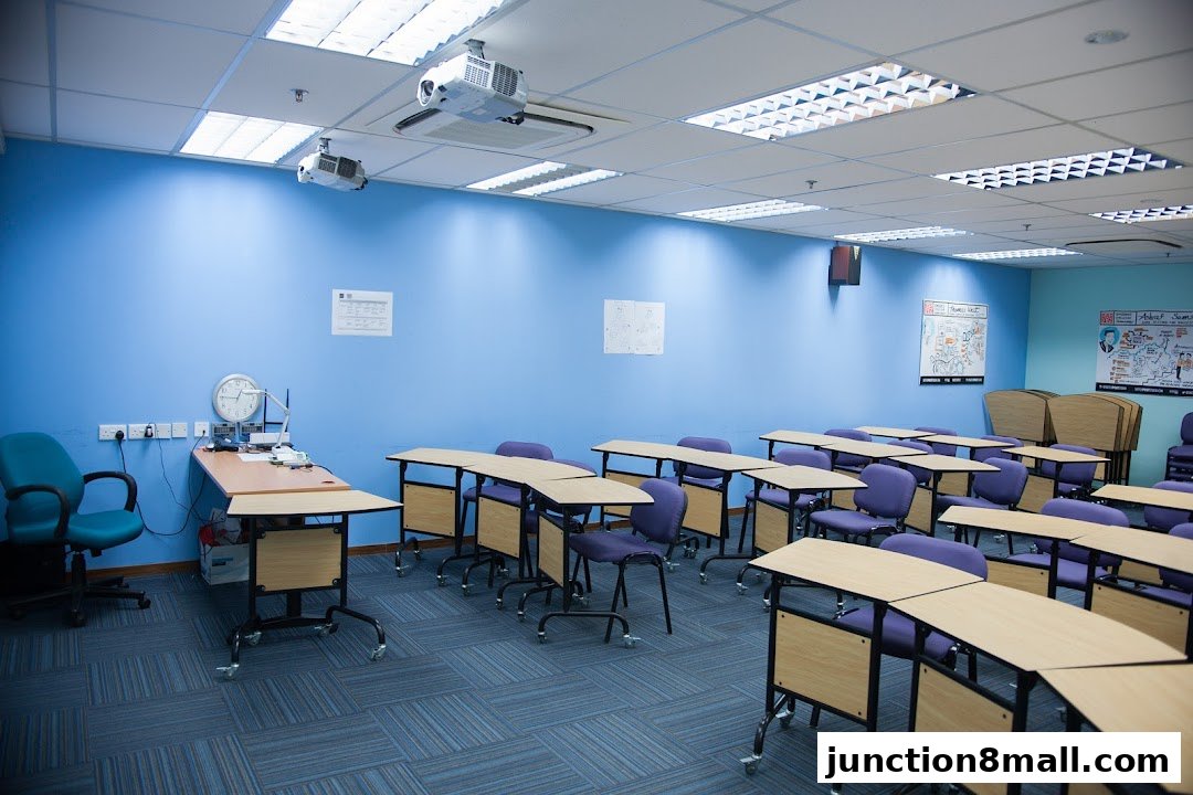 A modern classroom with blue walls, rows of desks with purple chairs, and projectors on the ceiling.