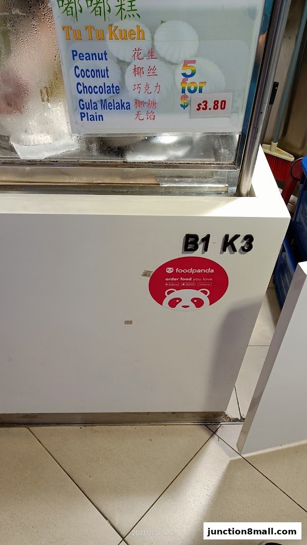 A display case showing various flavors of Tu Tu Kueh with prices and a Foodpanda sticker.