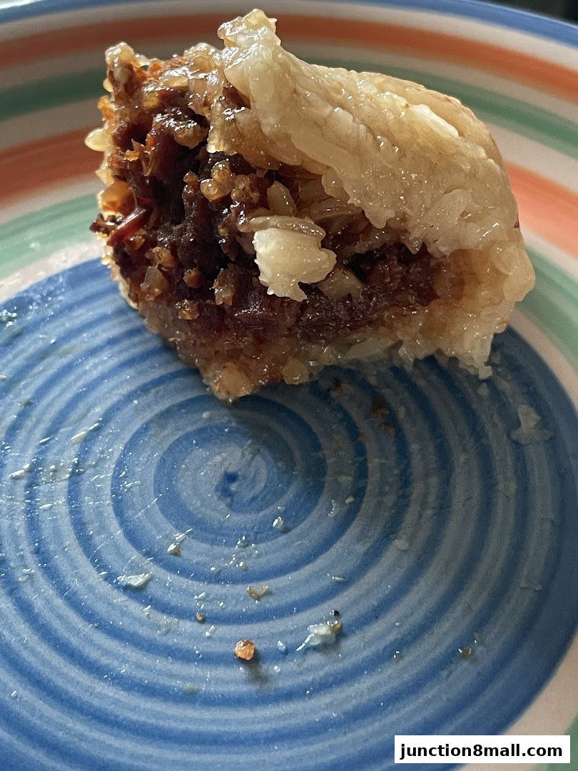 A close-up of a delicious rice dumpling with a savory filling on a colorful striped plate.