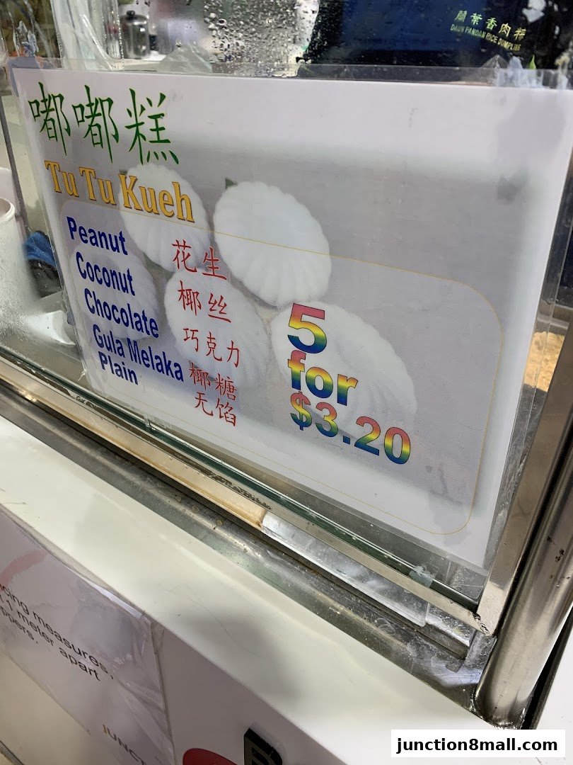 A sign displays various flavors of Tu Tu Kueh with prices and a special offer.