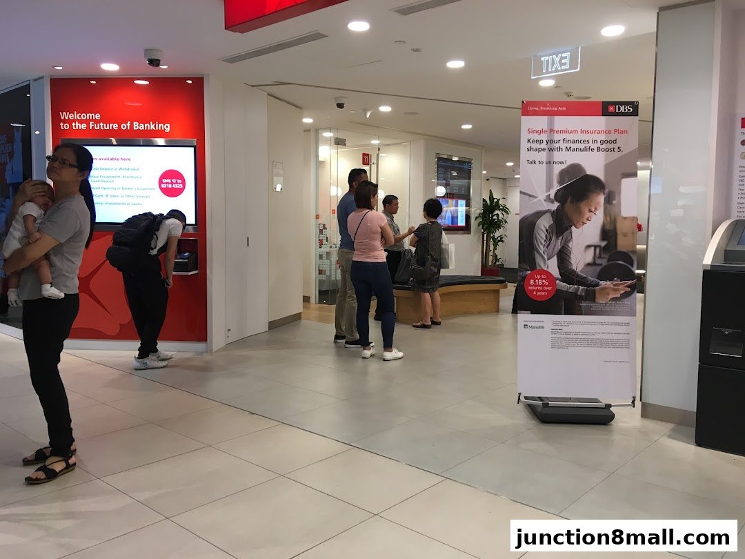 People at a DBS bank branch, with promotional posters and a digital display.