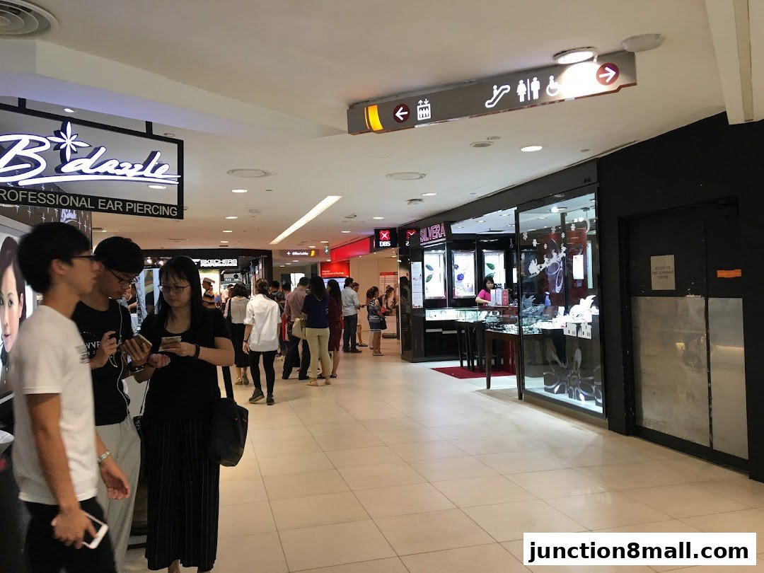 People walking in a mall hallway with shops on the right and a jewelry store.