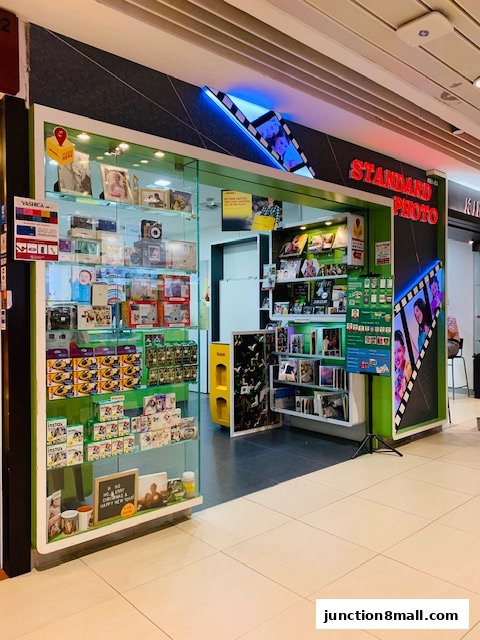 A brightly lit photo shop with displays of cameras, photo frames, and printing services.