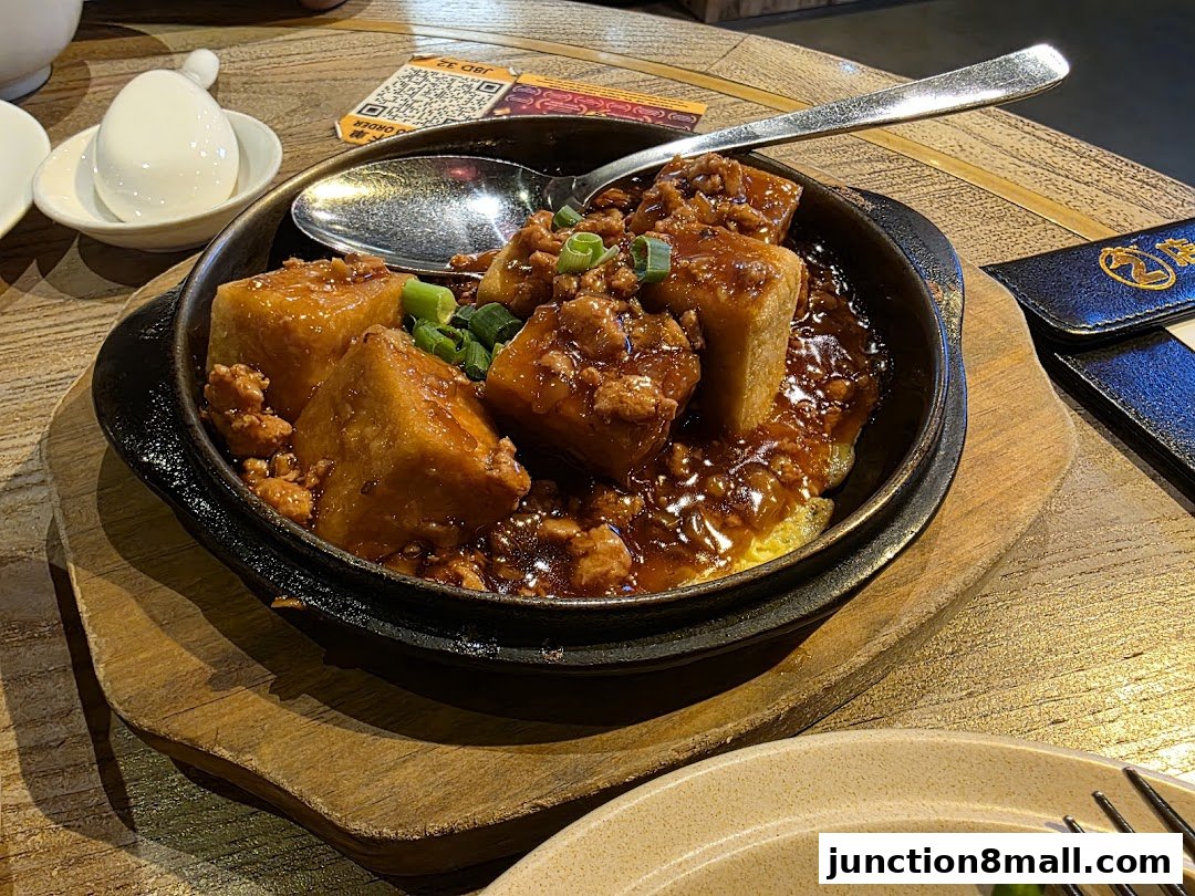 A sizzling dish of braised tofu with minced meat and scallions served in a cast iron pan.