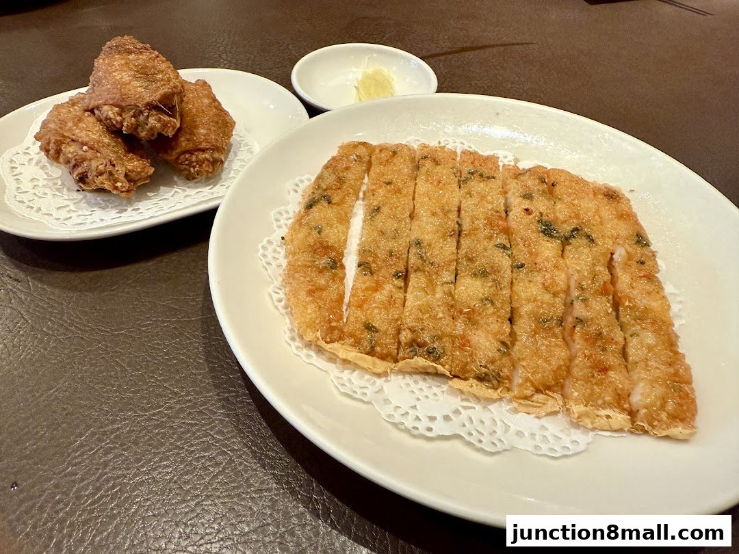 Two plates of delicious fried food, including chicken wings and sliced fried fish cakes.