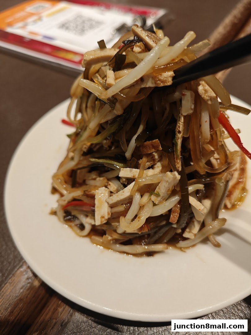 A close-up shot of a delicious salad with chopsticks picking up a portion.