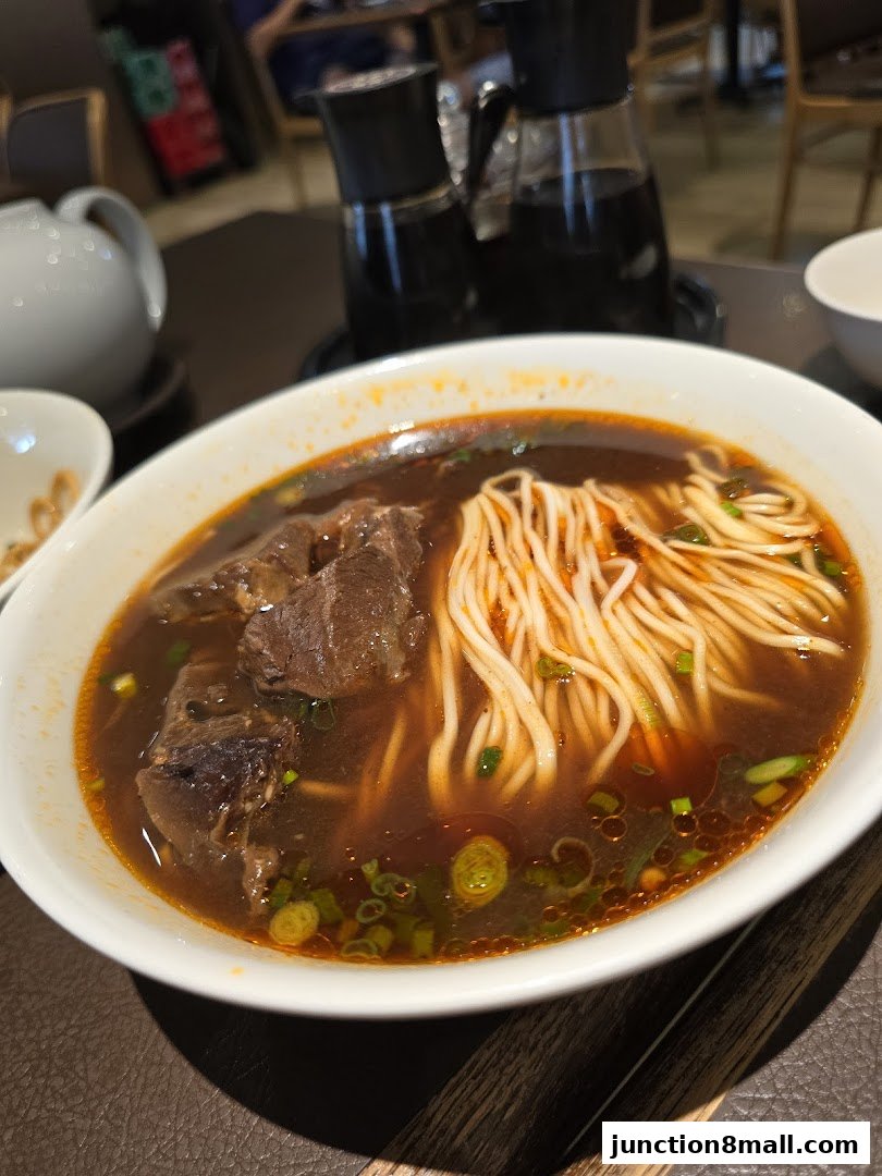 A close-up shot of a steaming bowl of beef noodle soup with tender beef chunks and noodles.