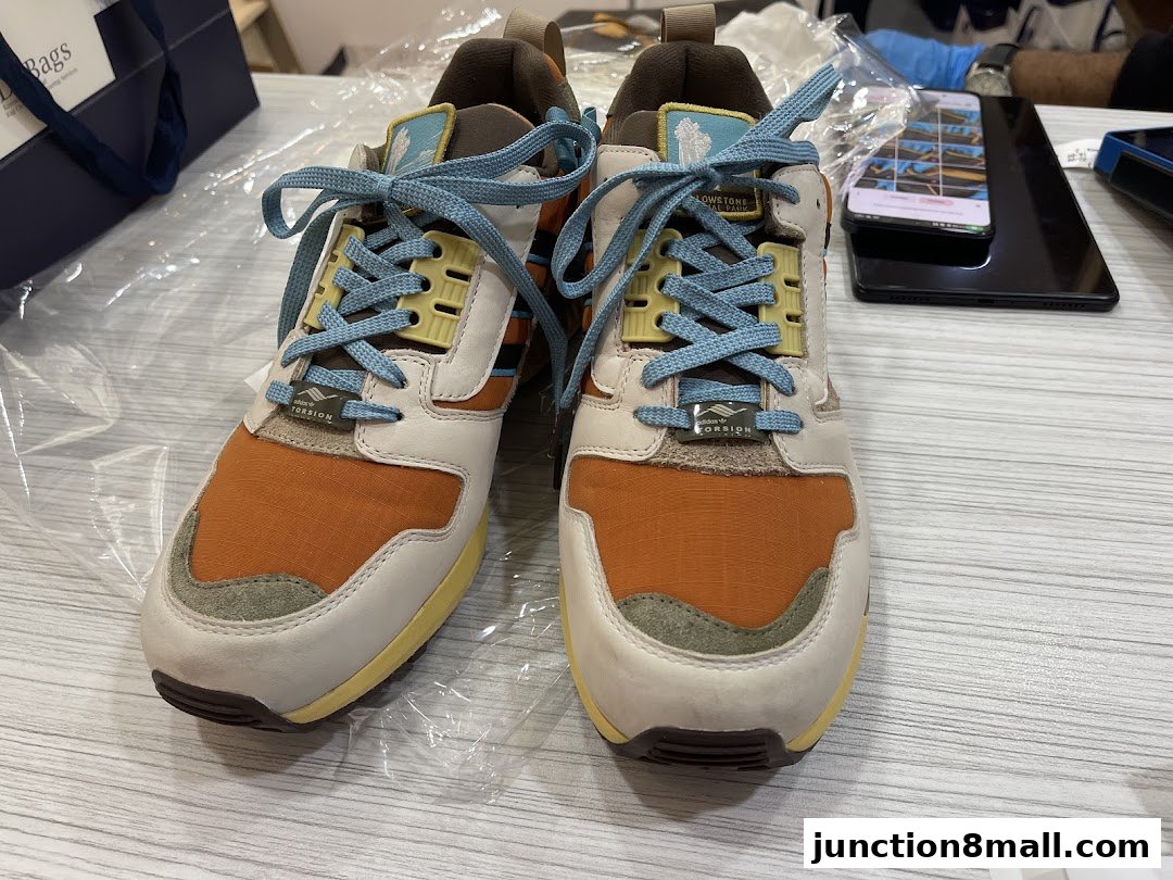 A pair of stylish Adidas sneakers with orange, white, and blue accents.