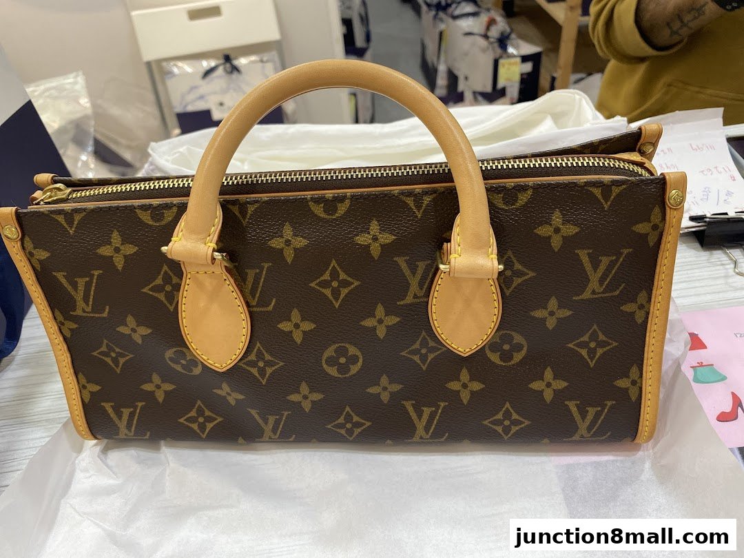 A close-up view of a brown Louis Vuitton monogrammed handbag with tan leather trim and handles.