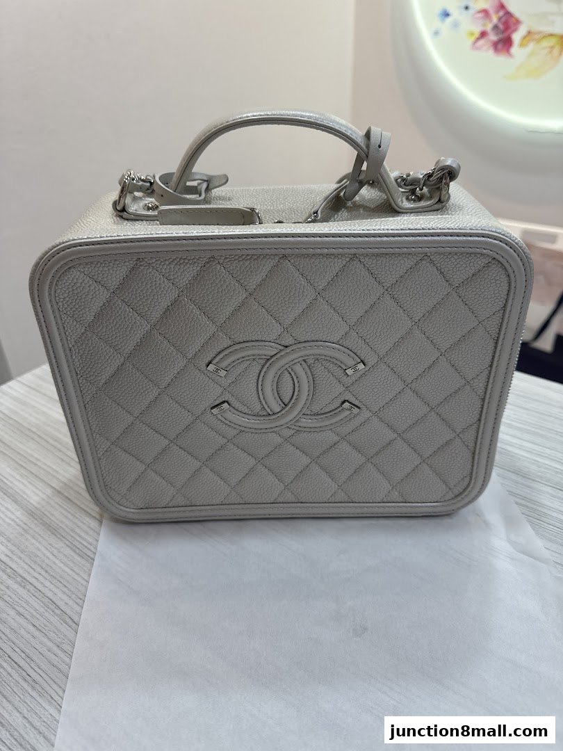 A close-up view of a light grey quilted handbag with a double C logo.