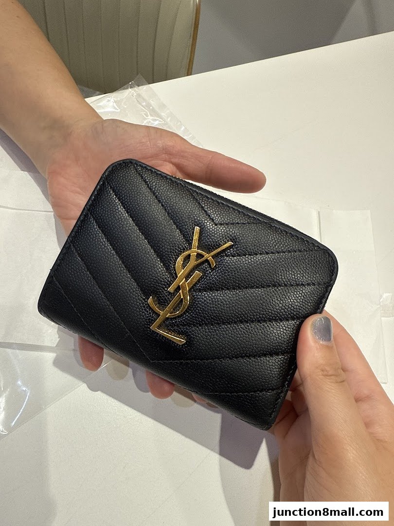 A black quilted wallet with a gold YSL logo is held by two hands.