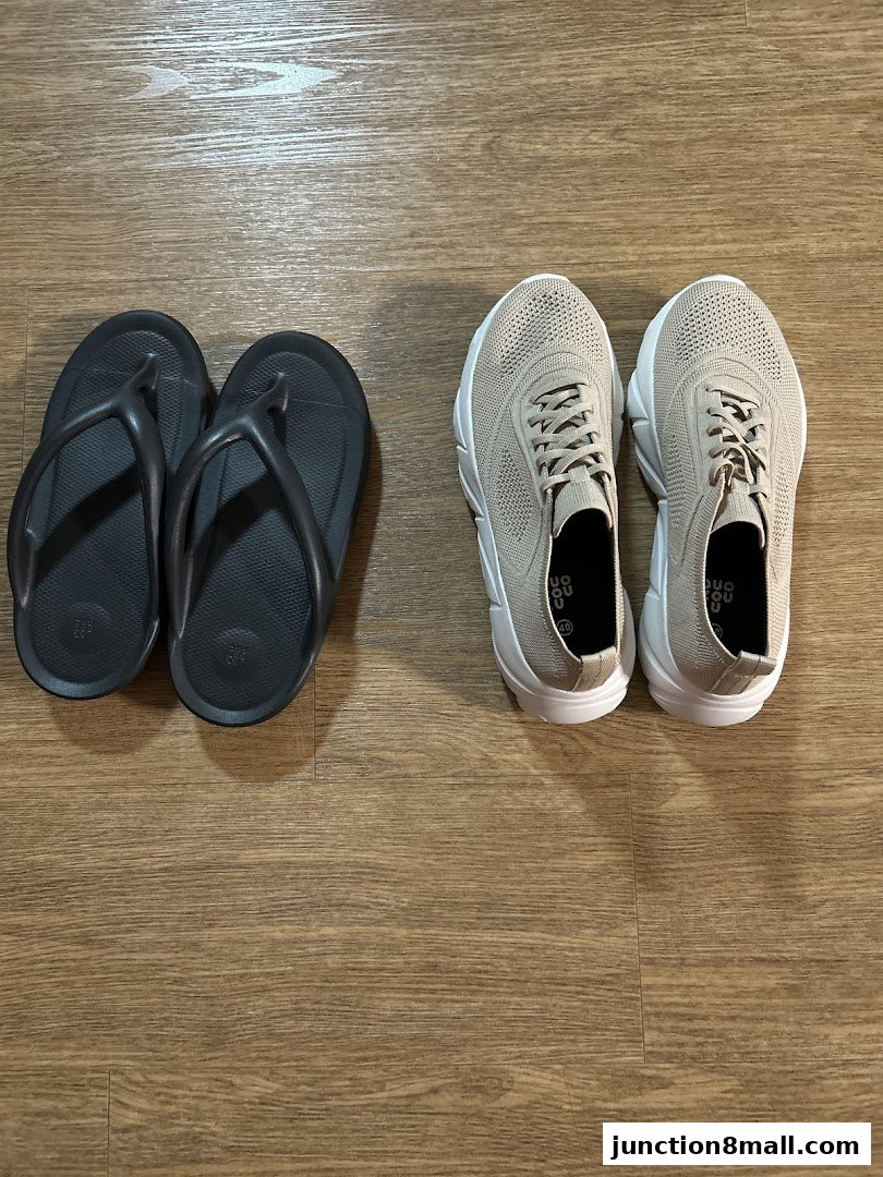 A pair of black flip-flops and a pair of beige sneakers are displayed on a wooden floor.
