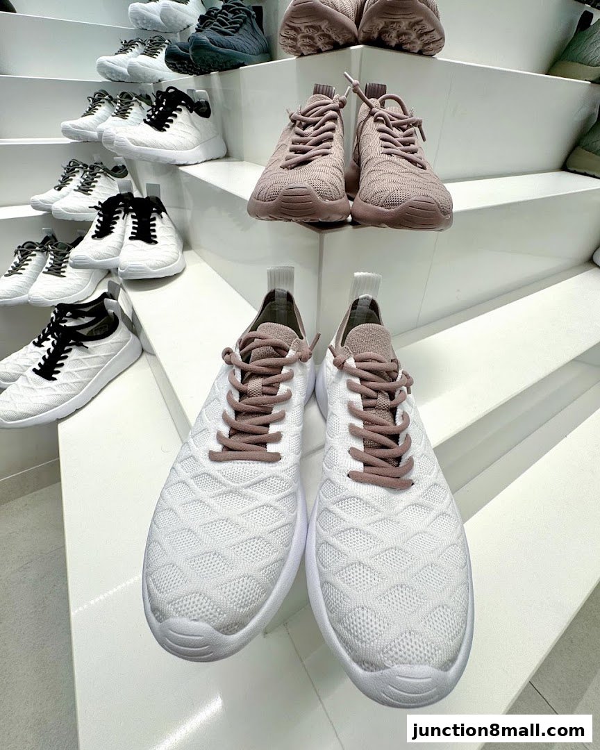 A display of various athletic shoes, with a focus on white and pink sneakers.